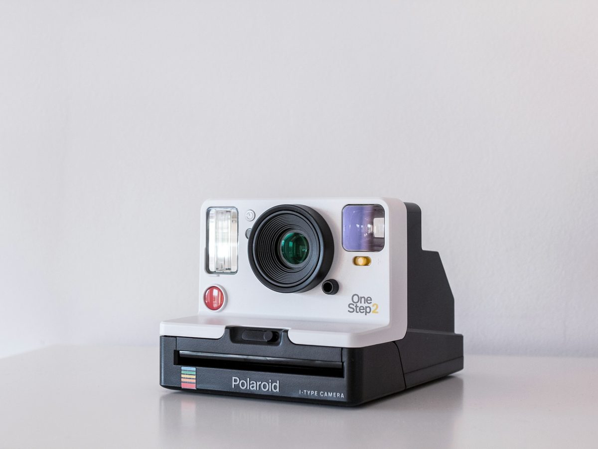 A white Polaroid OneStep 2 instant camera on a white table
